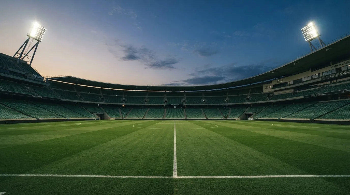 An empty football stadium with floodlight masts at dusk