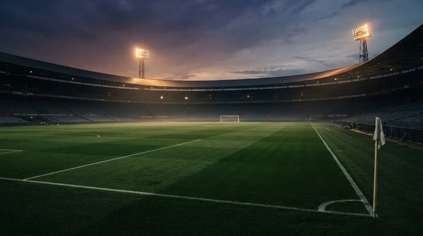 An empty football stadium with floodlight masts at dusk