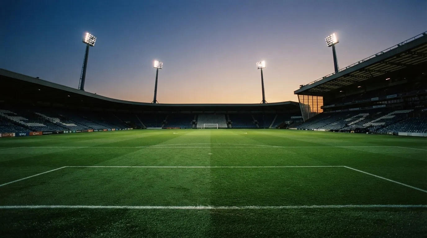 An empty football stadium with floodlight masts at dusk