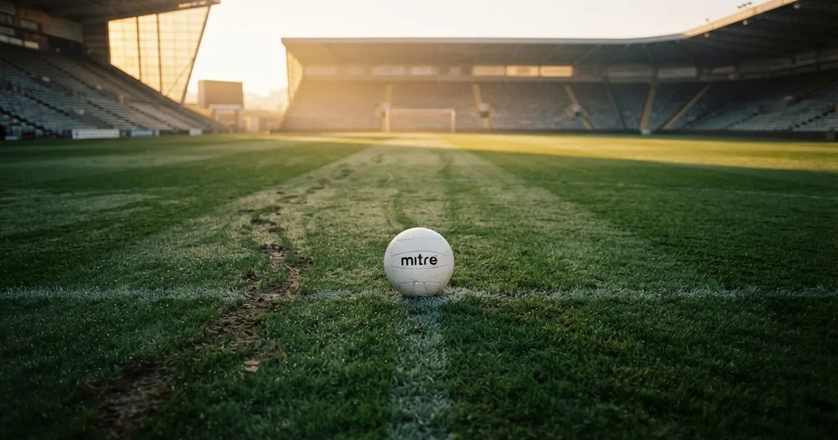 A ball on the centre spot of a grass pitch in morning light