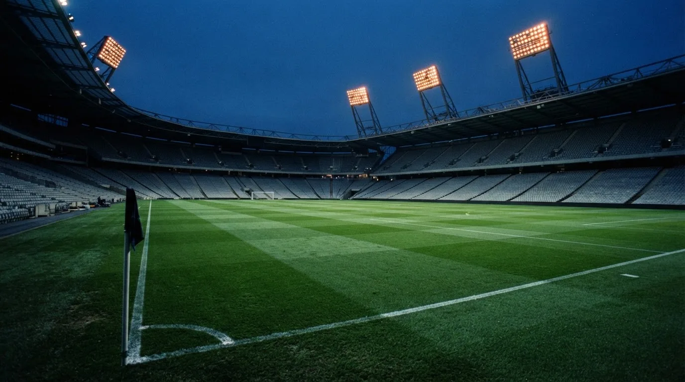 An empty football stadium with floodlight masts at dusk