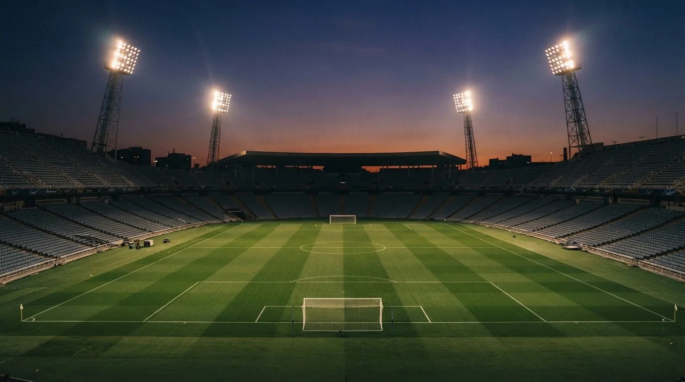 An empty football stadium with floodlight masts at dusk